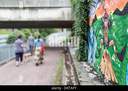 Menschen gehen unter Brücke neben Graffiti-Kunst von Pixie, Douai, Nord-Pas-de-Calais, Frankreich Stockfoto