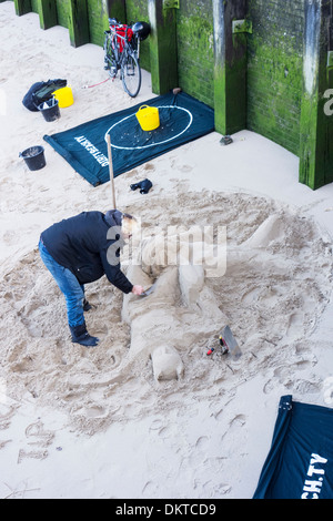 Ein Bildhauer schafft ephemere Figuren aus Sand vom Strand bei Ebbe auf der Themse auf der Southbank, London freigelegt Stockfoto