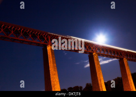 Vierte Brücke in der Nähe von Edinburgh mit einem vorbeifahrenden Zug und Mond bei Nacht. Stockfoto
