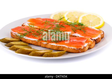 Lachs Sandwiches mit Gewürzgurken und Zitrone auf Platte isoliert auf weißem Hintergrund. Stockfoto