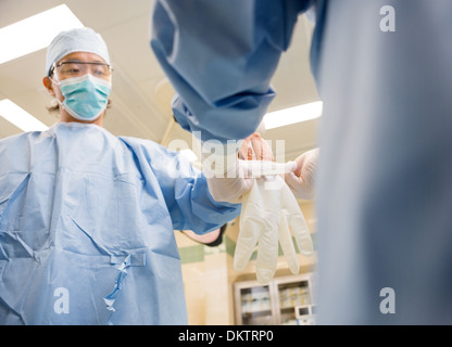 Krankenschwester helfen Chirurgen im Handschuh tragen Stockfoto