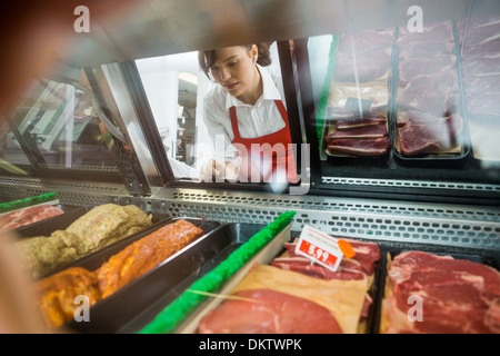 Verkäuferin, Blick auf die Vielzahl von Fleisch im Shop angezeigt Stockfoto