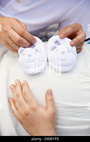 Nahaufnahme der Bauch einer schwangeren Frau mit Babyschuhe Stockfoto