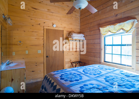 Einfache Schlafzimmer Innenraum mit Bett und Eitelkeit in ein Log home Cottage in Texas, USA. Stockfoto