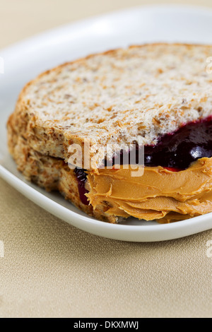 Closeup vertikale Foto von Erdnussbutter und Marmelade Sandwich, halbieren, in weißen Teller auf strukturierte Tischdecke unter Stockfoto