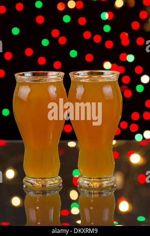 Vertikale Foto von zwei große Gläser am Tisch aus Glas, gefüllt mit Premium Amber Ale mit Party Lichter im Hintergrund Stockfoto