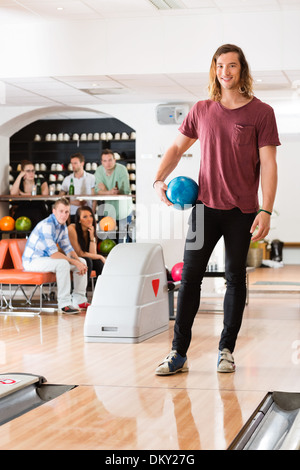 Junger Mann Holding Ball am Bowling-Club Stockfoto