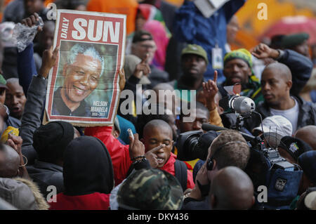 Johannesburg, Südafrika. 10. Dezember 2013. Personen ein Porträt von Nelson Mandela vor der Trauerfeier für den ehemaligen südafrikanischen Präsidenten an das FNB-Stadion in Soweto nahe Johannesburg, Südafrika, 10. Dezember 2013. Bildnachweis: Zhang Chen/Xinhua/Alamy Live-Nachrichten Stockfoto