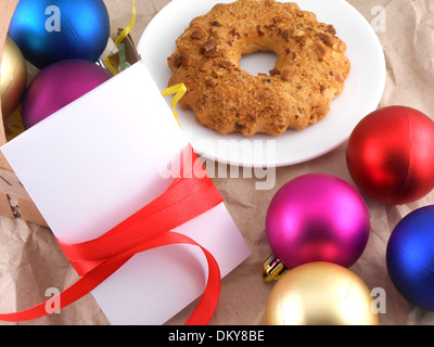 Kuchen mit Weihnachtskugeln und weiße Einladungskarte Stockfoto