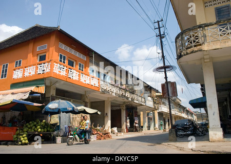 Zwei junge Frauen fahren auf einem kleinen Motorrad unter einem hellen Orange aufbauend auf einer Stadtstraße in Battambang, Kambodscha. Stockfoto