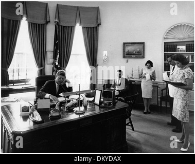 Präsident John F. Kennedy spricht telefonisch über die AMVETS-Konvention in New York City mit Assistenten im Weißen Haus. Die Veranstaltung fand während seiner Präsidentschaft statt, wobei er seine Kommunikation mit Veteranen hervorhob. Stockfoto