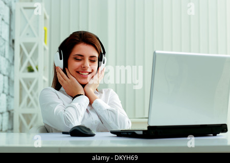 Junge schöne Geschäftsfrau hören von Musik im Kopfhörer im Büro Stockfoto