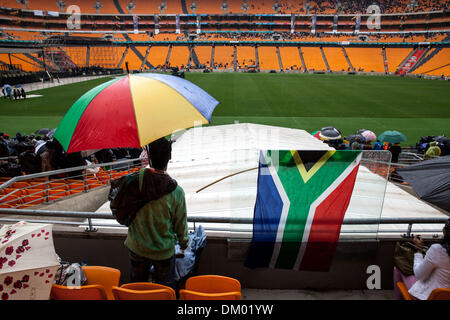 Soweto, Südafrika. 10. Dezember 2013. Ein Trauernder steht im Regen am ehemaligen Präsidenten Nelson Mandela Trauerfeier im FNB-Stadion in Johannesburg, am 10. Dezember 2013 in Soweto, Südafrika statt. Der Vater der Nation starb ruhig am Abend des 5. Dezember 2013 in seinem Haus in Houghton mit Familie. Er wird in Qunu für die offiziellen Staatsbegräbnis am 15. Dezember 2013 begraben werden. Bildnachweis: Gallo Bilder/Alamy Live News Stockfoto