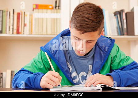 Männlichen Teenager konzentriert Hausaufgaben in einem Schreibtisch Stockfoto