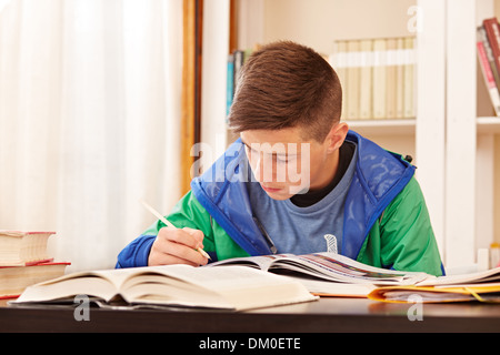 Männlichen Teenager konzentriert Hausaufgaben in einem Schreibtisch Stockfoto