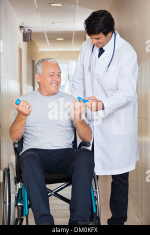 Arzt der Senior Mann sitzt In einer Wheelc Hand Gewichte verleihen Stockfoto