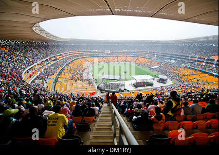 Johannesburg, Südafrika. 10. Dezember 2013. Tausende von Menschen versammelt, um die letzte Ehre, des verstorbenen ehemaligen südafrikanischen Präsidenten, Nelson Mandela, während der offiziellen National Memorial Service Zahlen auf das FNB-Stadion in Soweto, Johannesburg statt. Trauernde singen im Regen während der Feier. Foto: ImageSA/Alamy Live-Nachrichten Stockfoto