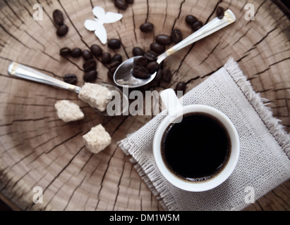 Getönten Bild, Tasse Kaffee, Kaffeebohnen, brauner Zucker, Löffel, hölzernen Hintergrund, weißes Papier Schmetterling Stockfoto