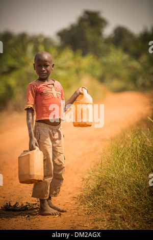 Ein Kind trägt Gießkannen Hause in Gombe, Uganda, Ostafrika. Stockfoto