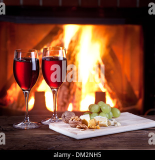 Romantisches Stilleben am Kamin. Gläser Wein, Käse und Nüssen. Stockfoto