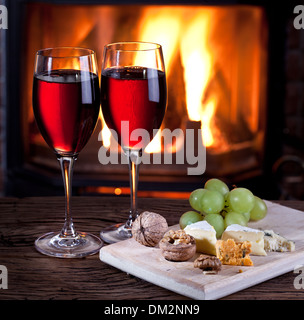 Romantisches Stilleben am Kamin. Gläser Wein, Käse und Nüssen. Stockfoto