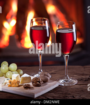 Romantisches Stilleben am Kamin. Gläser Wein, Käse und Nüssen. Stockfoto