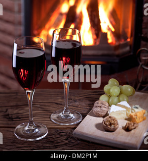 Romantisches Stilleben am Kamin. Gläser Wein, Käse und Nüssen. Stockfoto