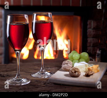 Romantisches Stilleben am Kamin. Gläser Wein, Käse und Nüssen. Stockfoto