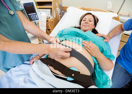 Krankenschwester anbringen Fetal Monitor zur Geburt Mutter Stockfoto