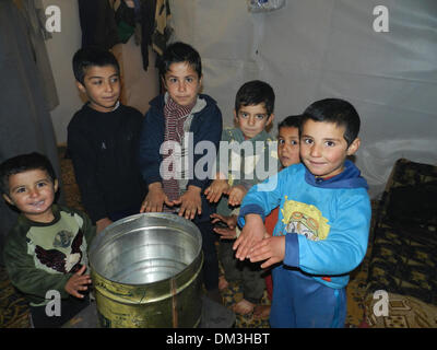 (131211)--BEIRUT, 11. Dezember 2013 (Xinhua)--syrischer Flüchtling Kinder versammeln sich um einen Herd zum warm werden in einem Flüchtlingslager im Südlibanon, 11. Dezember 2013. Da der Winter vor der Tür ist, wird wie die kalte Temperaturen ertragen zum Problem für syrische Flüchtlinge im Libanon. (Xinhua) (Dzl) Stockfoto