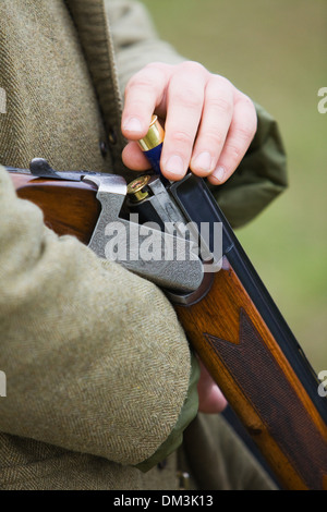 A Mann, laden 12 Bohrung oder Schrotflinte auf einem Fasan schießen in England zu messen Stockfoto