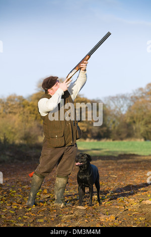 Ein schwarzer Labrador Retriever mit seinem Besitzer auf einem Fasan schießen in England Stockfoto
