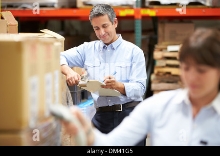 Manager im Lager mit Arbeiter Scan Box im Vordergrund Stockfoto