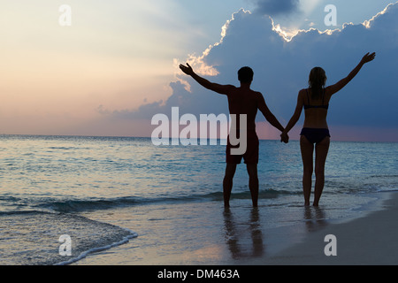 Silhouette eines Paares zu Fuß am Strand bei Sonnenuntergang Stockfoto