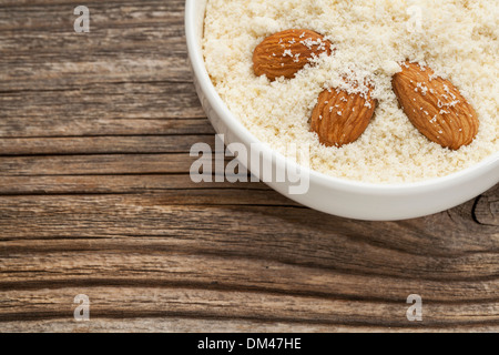 Mandel Mehl hoher Proteingehalt, wenig Kohlenhydrate, wenig Zucker und Gluten-frei - eine Keramikschale auf gemasertem Holz Hintergrund Stockfoto