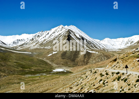 Ladakh, Indien - Juli 2009: Hochgebirge kurvenreiche Straße mit Schnee bedeckten Gipfeln Stockfoto