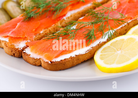 Lachs Sandwiches mit Gewürzgurken und Zitrone auf Platte Closeup Bild. Stockfoto