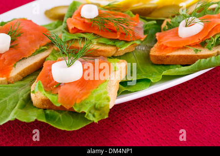 Lachs Sandwiches mit Salat, frische und eingelegte Gurken, Zwiebel, Zitrone auf Platte. Stockfoto