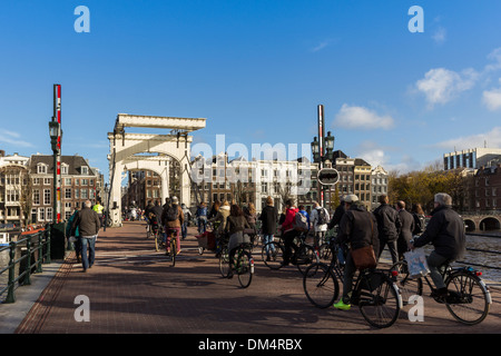 MAGERE BRÜCKE ÜBER DEN FLUSS AMSTEL AMSTERDAM MIT RADFAHRER UND WANDERER, DIE KREUZUNG AUF DER GEGENÜBERLIEGENDEN SEITE Stockfoto