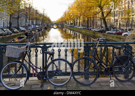 ZWEI FAHRRÄDER UND EINEM NIEDERLÄNDISCHEN KANAL MIT HERBSTLICHEN BÄUME IN AMSTERDAM HOLLAND Stockfoto