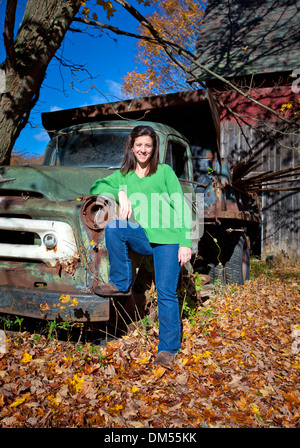 Hübsche Womwn stützte sich auf einem verlassenen alten LKW im Herbst Stockfoto