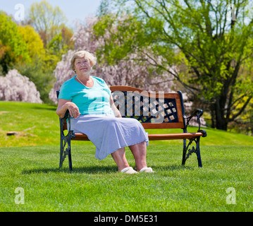 Reife Frau sitzen und ruhen auf einer Parkbank Stockfoto
