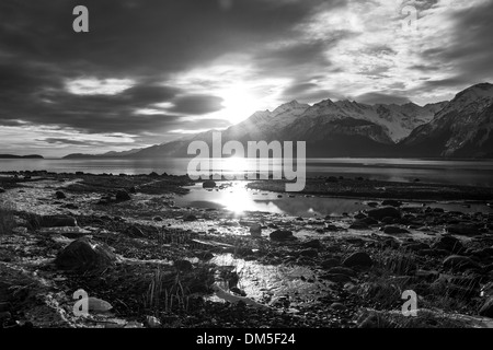 Untergehende Sonne an einem gefrorenen Strand in Southeast Alaska in schwarz und weiß. Stockfoto