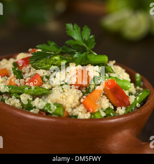 Vegetarische Quinoa Gericht mit grünem Spargel und rote Paprika, bestreut mit Petersilie in rustikalen Schüssel Stockfoto