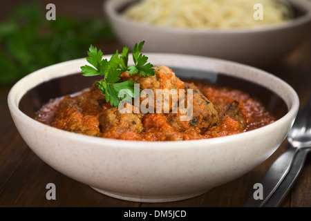 Spanische Albondigas (Fleischbällchen) in Tomatensoße in Schüssel geben, mit Petersilie garniert Stockfoto