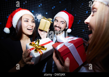 Porträt von fröhlichen Kollegen in Santa Mützen halten Crhistmas Geschenke in Nachtclub Stockfoto