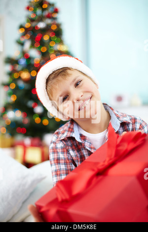 Porträt der fröhliche junge mit großen roten Geschenkbox Blick in die Kamera am Heiligen Abend Stockfoto