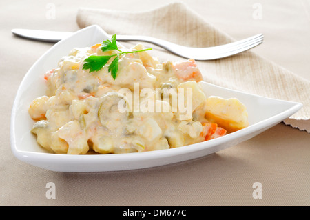 eine Platte mit einem typisch spanischen Ensaladilla Rusa, russischer Salat, auf einem gedeckten Tisch Stockfoto