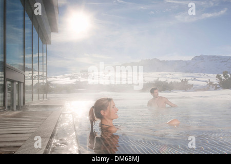 Frau und Mann sitzt in einen beheizten Swimming Pool im Winter bei dampfendem Wasser, Südtirol, Trentino-Alto Adige, Italien Stockfoto