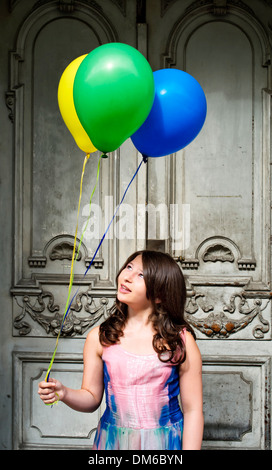 Mädchen mit Luftballons vor einer alten Tür Stockfoto